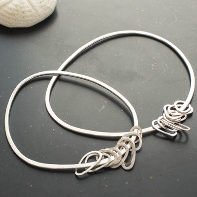 Sterling silver pebble shaped bangles with mini pebble shaped rings, handmade by cornish jeweller chloe michell